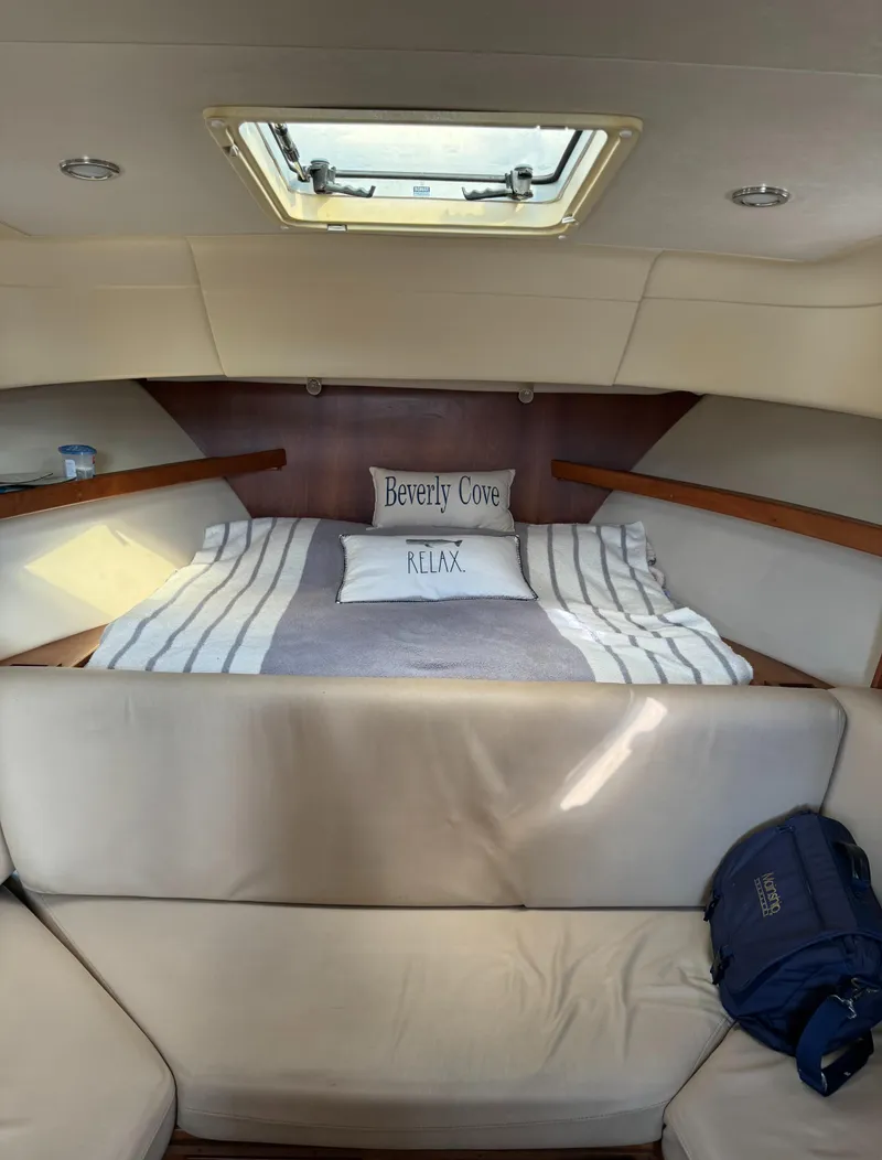 Slide: The Image of 2004 Mainship 30 Pilot II Express Cruiser cabin with bed, striped bedding, and overhead hatch. - 19