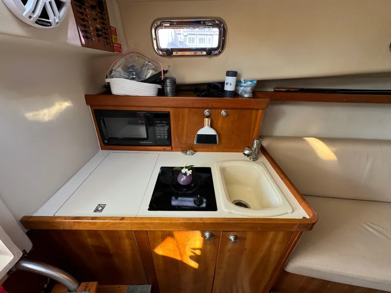 Slide: The Image of 2004 Mainship 30 Pilot II Express Cruiser interior kitchen with sink, stove, and microwave. - 20