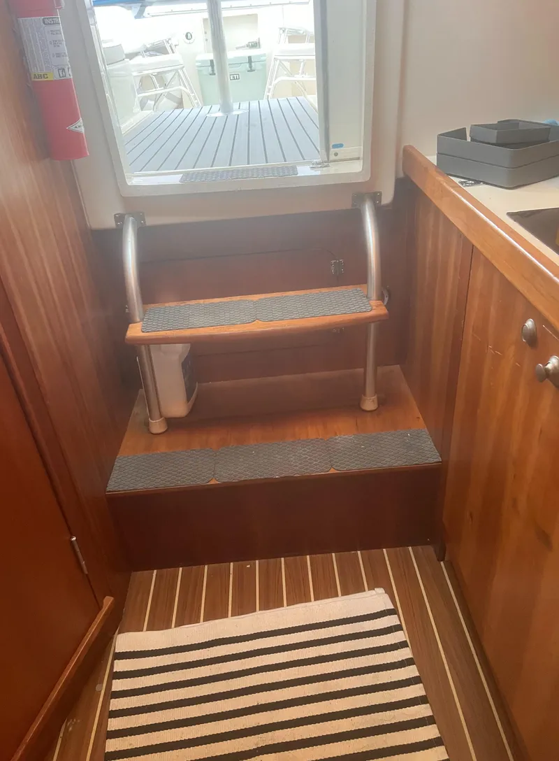 Slide: The Image of Interior of 2004 Mainship 30 Pilot II Express Cruiser with wooden steps and striped rug. - 22