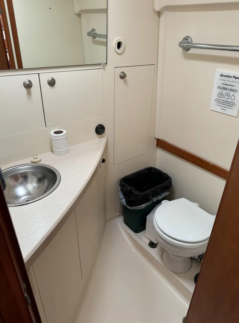 Slide: The Image of 2004 Mainship 30 Pilot II Express Cruiser bathroom with sink, toilet, and storage cabinets. - 24