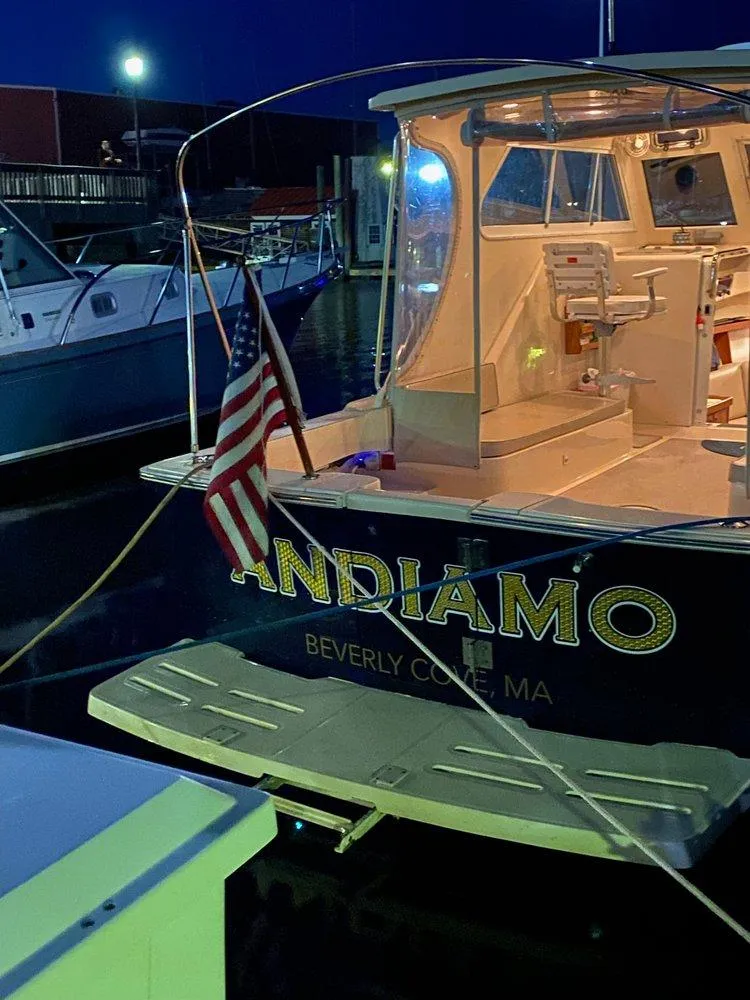 Slide: The Image of 2004 Mainship 30 Pilot II Express Cruiser docked at night with American flag. - 7