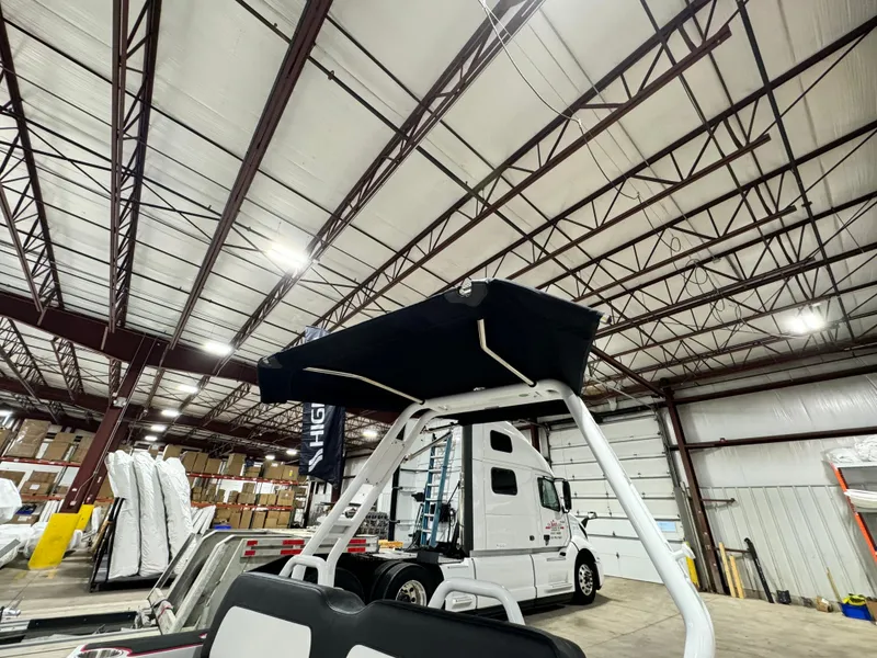 Slide: The Image of 2025 Highfield Velox 420 boat in warehouse, featuring a canopy and industrial setting. - 12