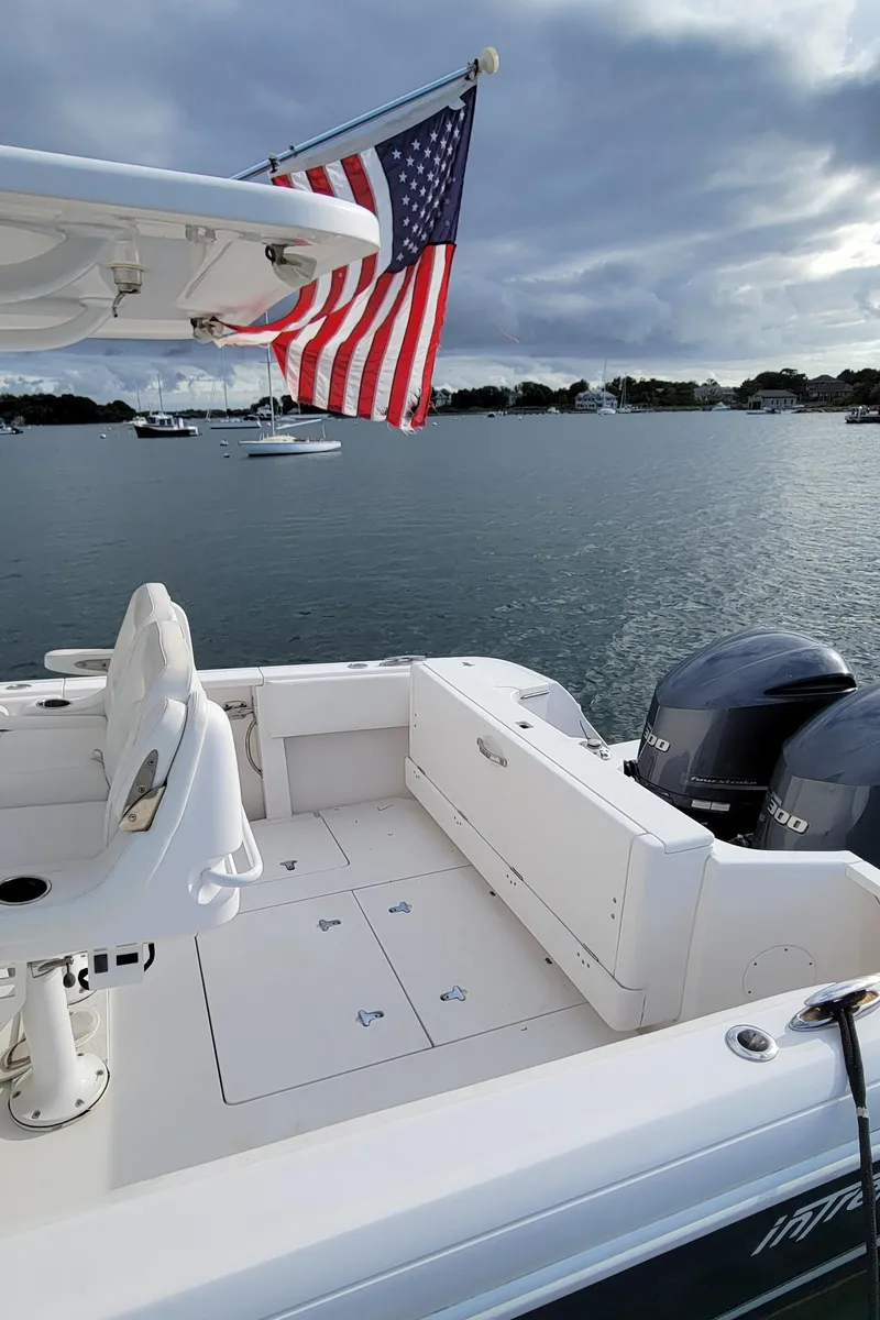 Slide: The Image of 2016 Intrepid 327 Cuddy boat with American flag on calm water. - 20