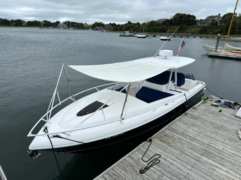 Slide: The Image of 2016 Intrepid 327 Cuddy boat docked with canopy, calm waters in background. - 24