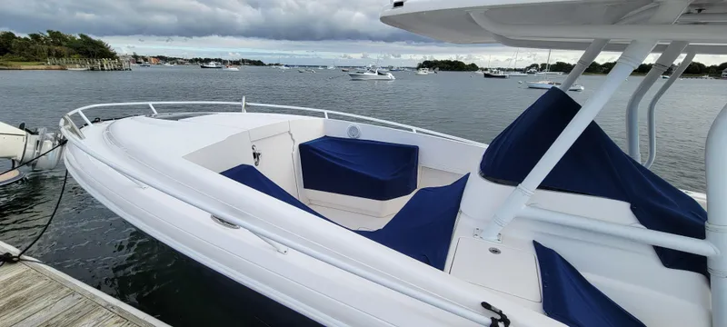 Slide: The Image of 2016 Intrepid 327 Cuddy boat docked with blue seating, scenic waterfront view. - 8