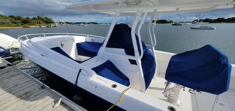 Slide: The Image of 2016 Intrepid 327 Cuddy boat docked, featuring blue seat covers and sleek design. - 9