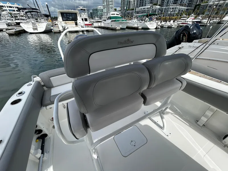 Slide: The Image of 2021 NauticStar 2102 Legacy boat interior with gray seating at marina. - 10