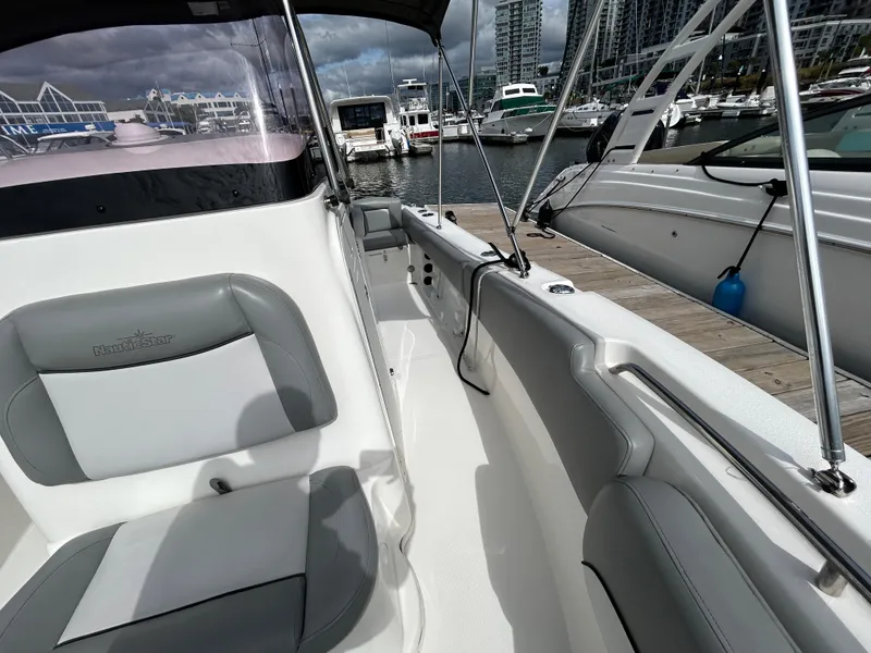 Slide: The Image of 2021 NauticStar 2102 Legacy boat docked at marina, featuring sleek seating and modern design. - 15