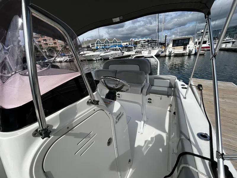 Slide: The Image of 2021 NauticStar 2102 Legacy boat docked at marina, showcasing helm and seating area. - 16