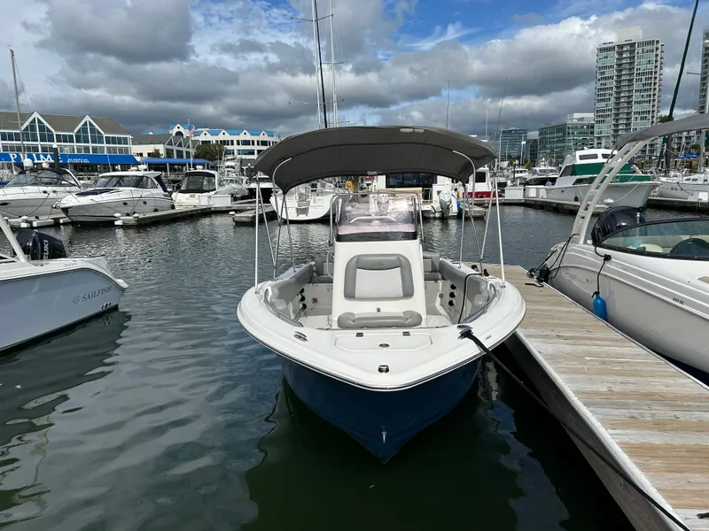 Slide: The Image of 2021 NauticStar 2102 Legacy boat docked in a marina with cloudy skies. - 2