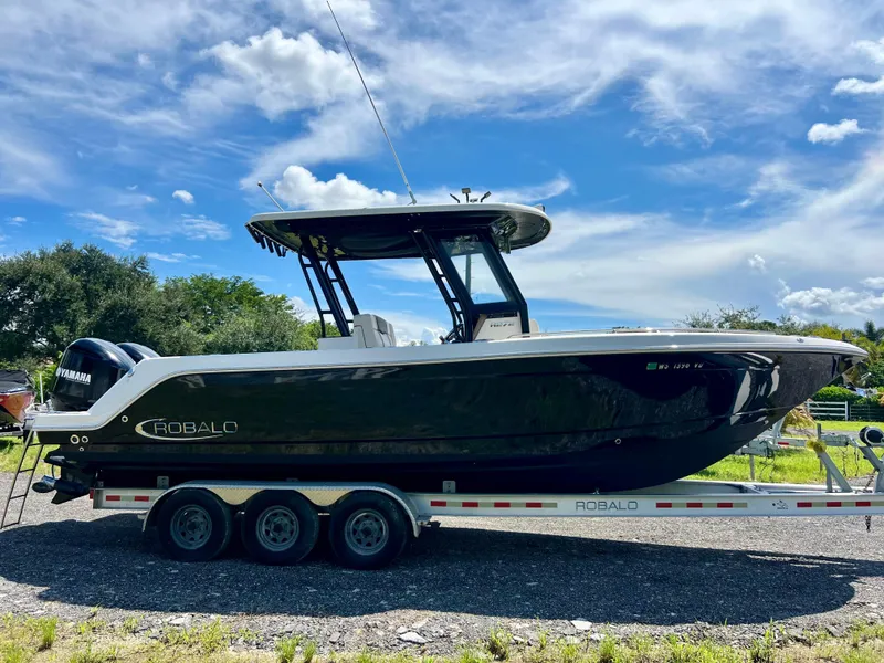 Slide: The Image of 2021 Robalo R272 Center Console boat on trailer under blue sky. - 1