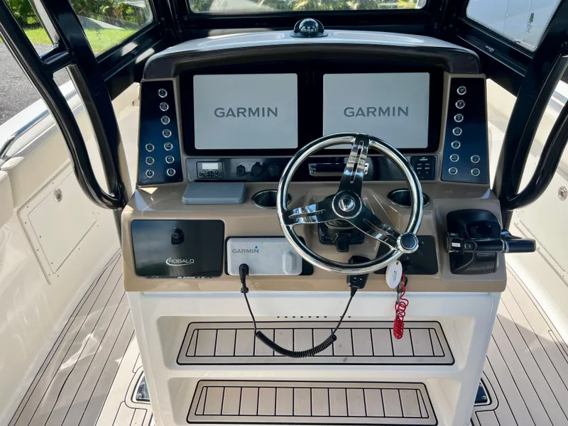 Slide: The Image of 2021 Robalo R272 Center Console boat dashboard with dual Garmin displays and steering wheel. - 13