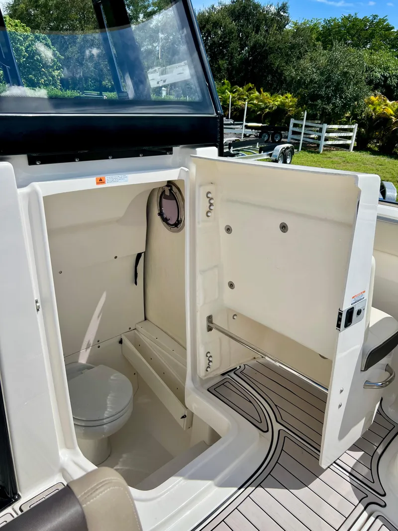 Slide: The Image of 2021 Robalo R272 Center Console boat interior with open storage compartment and toilet. - 20