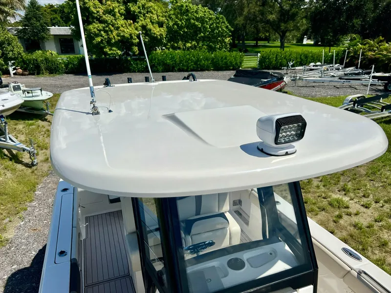 Slide: The Image of 2021 Robalo R272 Center Console boat with hardtop and spotlight, parked outdoors. - 40