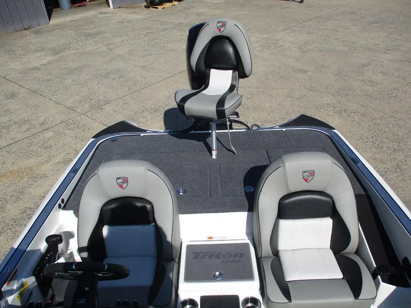 Slide: The Image of 2025 Triton 18 TrX boat interior with three gray and black seats on a sunny day. - 10