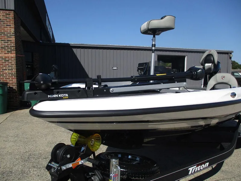 Slide: The Image of 2025 Triton 18 TrX boat with Minn Kota trolling motor, parked outdoors. - 11