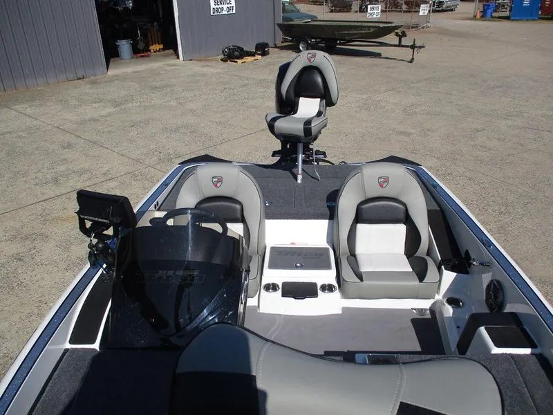 Slide: The Image of 2025 Triton 18 TrX boat interior with gray seating and console, parked outdoors. - 7
