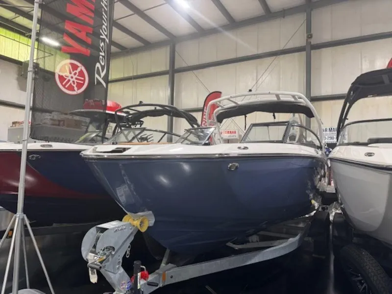 The Image of 2025 Yamaha Boats 252S displayed indoors, blue hull, on a trailer. - 1