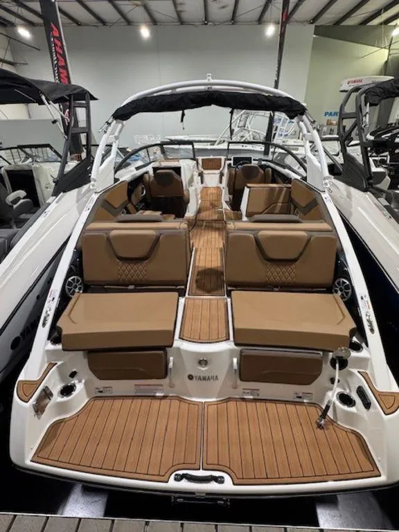 Slide: The Image of 2025 Yamaha Boats 252S interior with tan seating and wood flooring in showroom. - 5