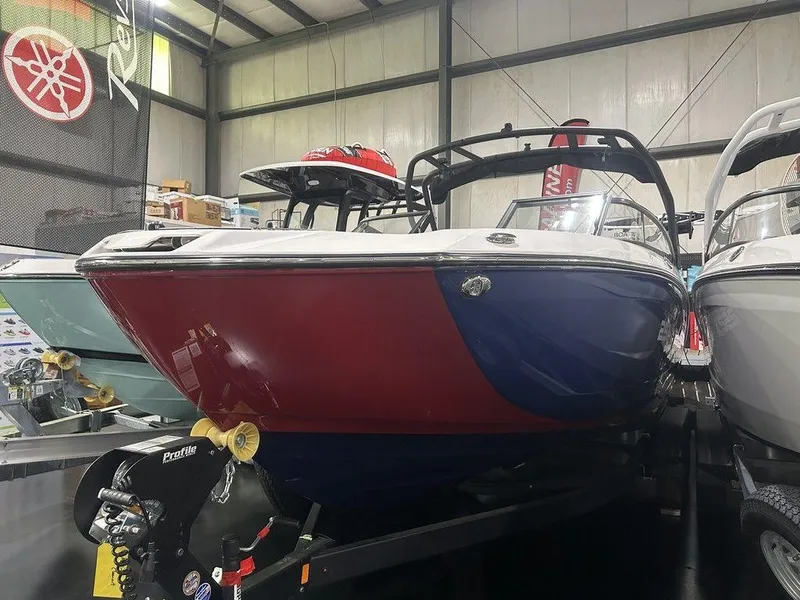 Slide: The Image of 2025 Yamaha Boats 252XE in showroom, red and blue hull, displayed on trailer. - 6