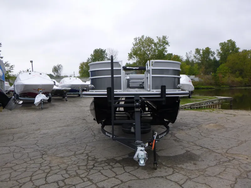 Slide: The Image of 2024 Ranger Reata 223C pontoon boat on trailer, parked near a lake. - 10