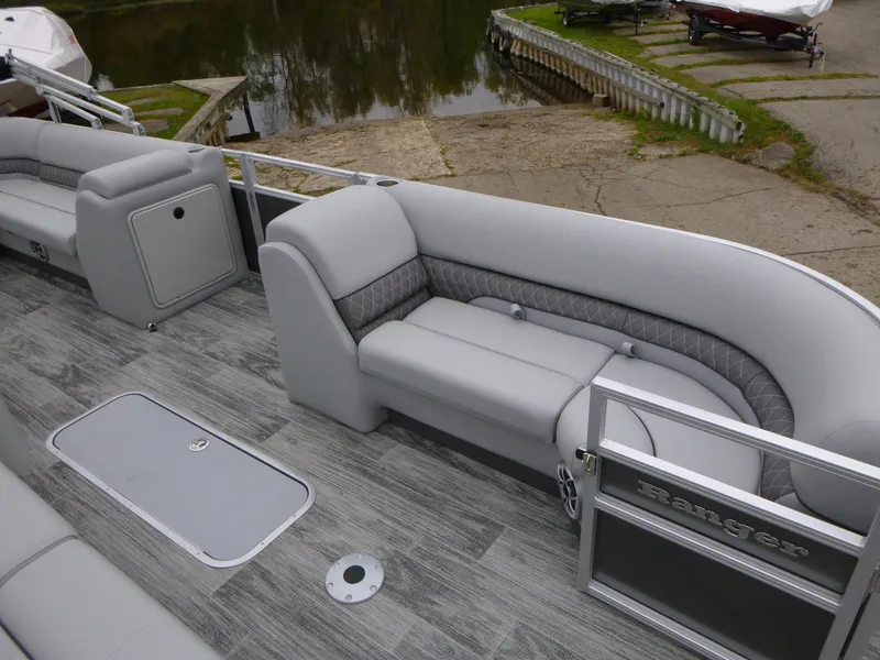 Slide: The Image of 2024 Ranger Reata 223C pontoon boat with gray seating and deck, docked by a lake. - 17