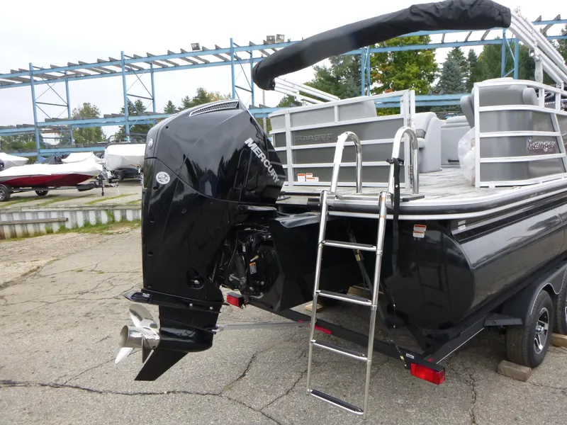 Slide: The Image of 2024 Ranger Reata 223C boat with Mercury outboard motor and ladder, parked on a trailer. - 2