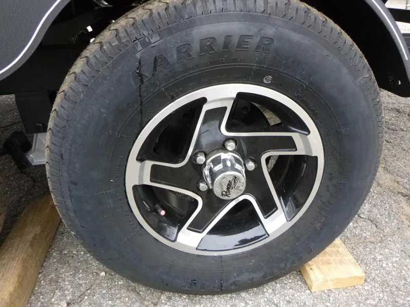 Slide: The Image of 2024 Ranger Reata 223C wheel with black and silver rim on wooden block. - 34