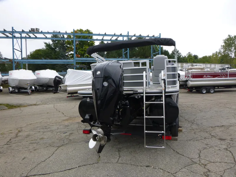 Slide: The Image of 2024 Ranger Reata 223C pontoon boat with outboard motor and ladder, parked outdoors. - 36