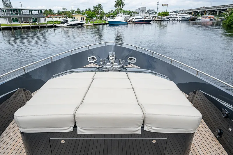 Slide: The Image of 2014 Pershing 92 yacht bow with cushioned sunbathing area, docked in a marina. - 38