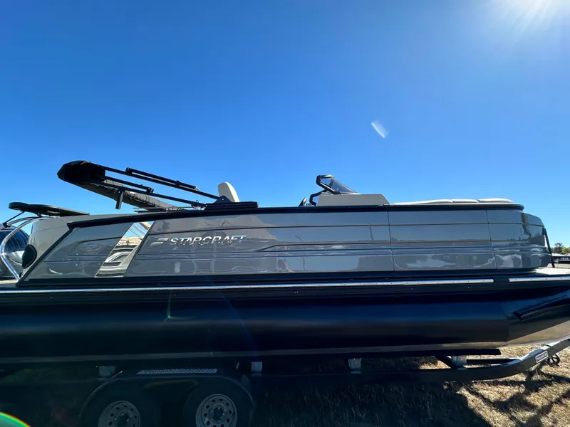 The Image of 2024 Starcraft RX23QDC 3.0 boat on trailer under clear blue sky. - 0