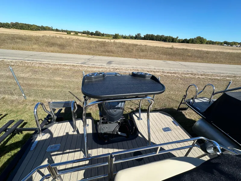 Slide: The Image of 2024 Starcraft RX23QDC 3.0 boat deck with table and railing, set against a grassy landscape. - 19