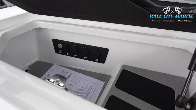 Slide: The Image of 2025 Nautique Super Air Nautique G23 storage compartment with control panel and documents. - 30