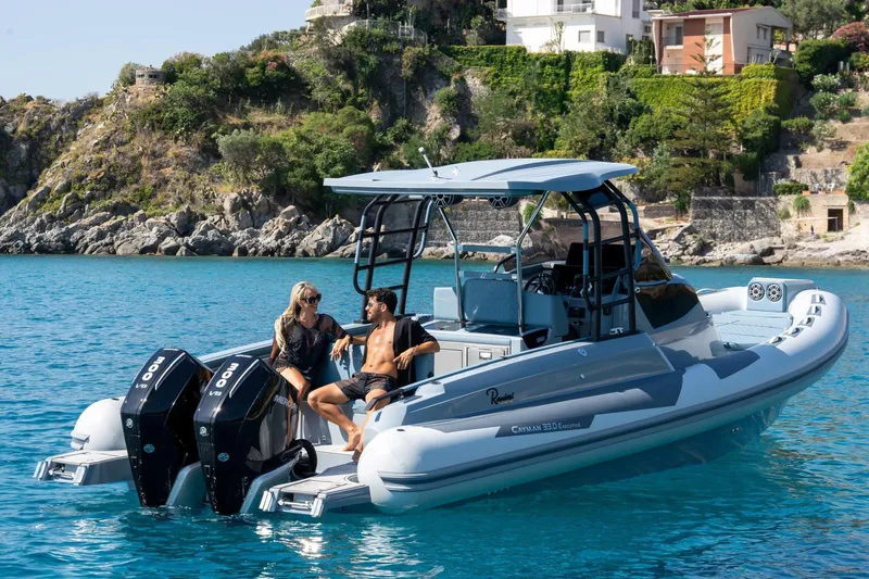Slide: The Image of 2025 Ranieri Cayman 33 Executive boat on clear blue water near rocky coastline. - 4