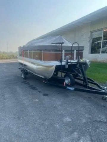 Slide: The Image of 2022 Bennington 168 SF pontoon boat on trailer, covered, parked outside a building. - 12