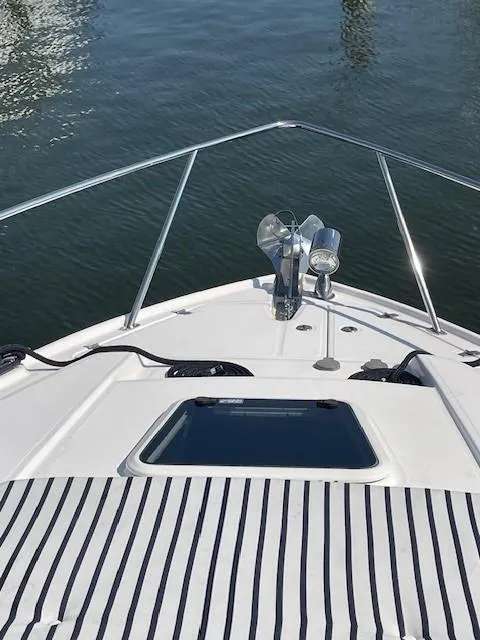 Slide: The Image of 2018 Regal 35 Sport Coupe boat bow with striped sun pad and water view. - 6