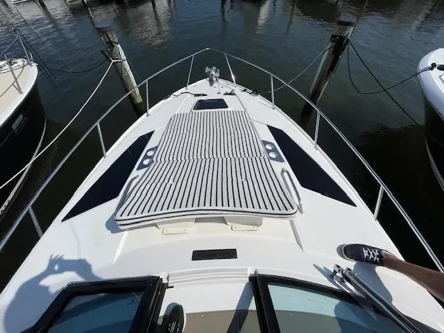 Slide: The Image of 2018 Regal 35 Sport Coupe boat deck with striped sun pad, docked at marina. - 8