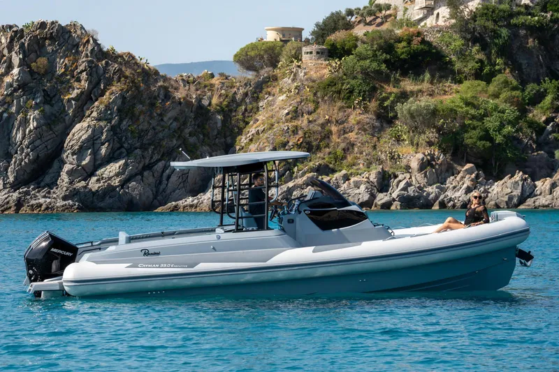 The Image of 2025 Ranieri Cayman 33 Executive boat cruising near rocky coastline. - 0