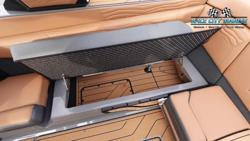 Slide: The Image of 2025 Nautique Super Air Nautique G25 interior storage compartment with tan upholstery and wood flooring. - 25