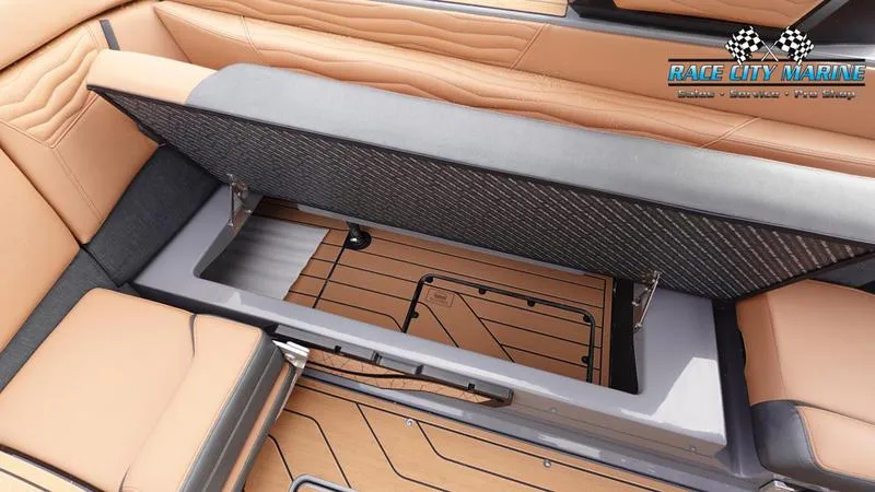 Slide: The Image of 2025 Nautique Super Air Nautique G25 interior storage compartment with tan seating and Race City Marine logo. - 26