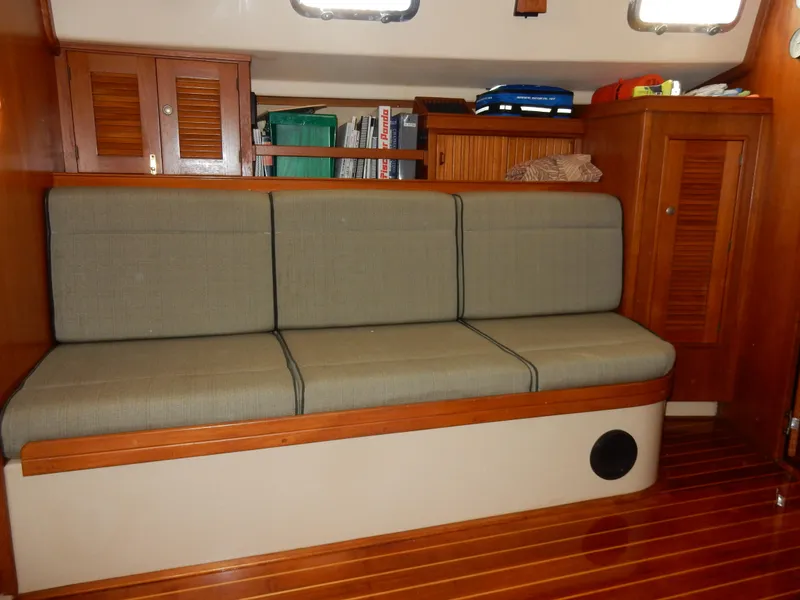 Slide: The Image of Interior of 1997 Island Packet 40 sailboat with cushioned seating and wooden cabinetry. - 11