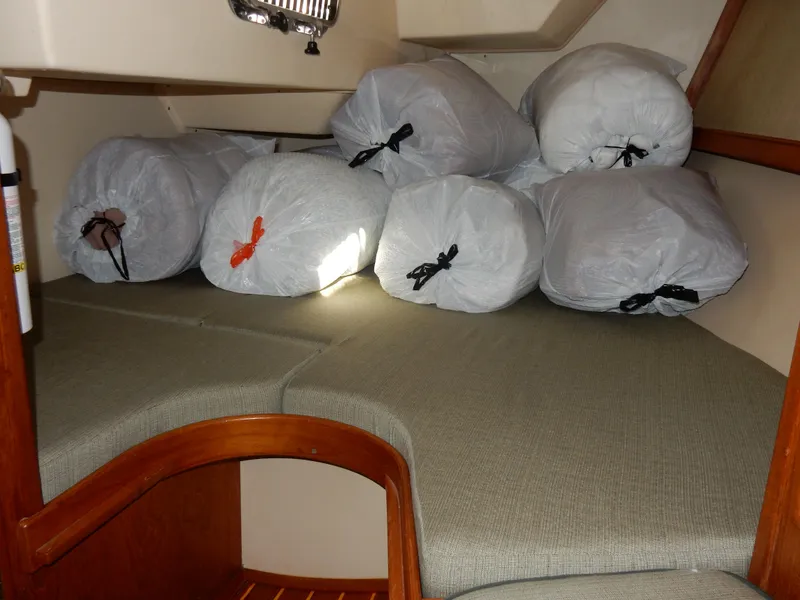 Slide: The Image of 1997 Island Packet 40 interior with storage bags on cushioned seating area. - 14