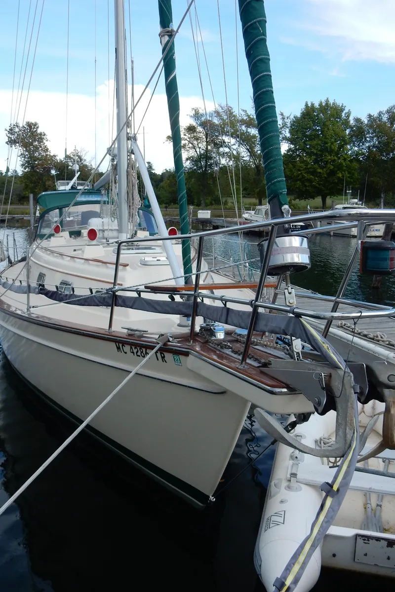 Slide: The Image of 1997 Island Packet 40 sailboat docked in a marina, surrounded by trees and calm water. - 2