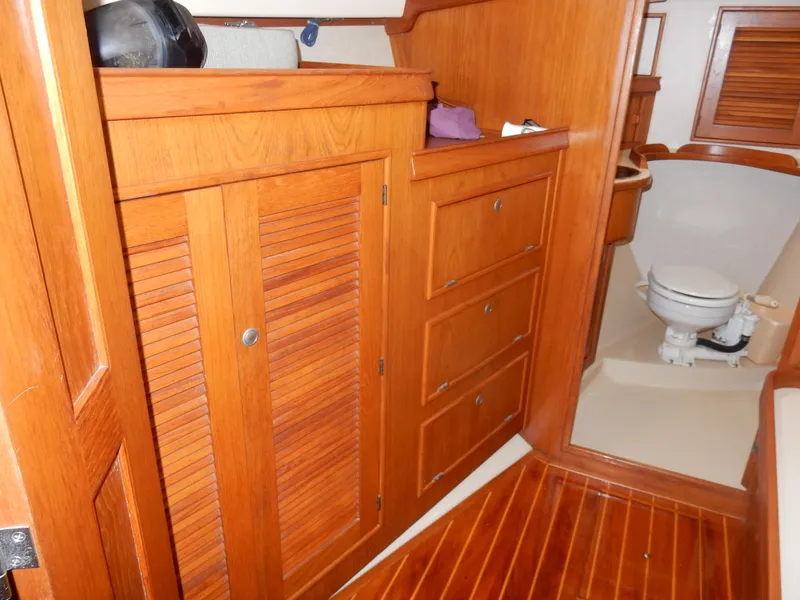 Slide: The Image of Interior of 1997 Island Packet 40 sailboat with wooden cabinetry and marine toilet. - 26