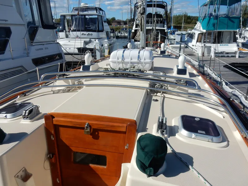 Slide: The Image of 1997 Island Packet 40 sailboat deck with wooden hatch, docked among other boats. - 41