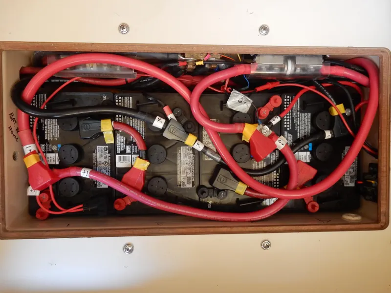 Slide: The Image of Battery compartment with red cables in a 1997 Island Packet 40 sailboat. - 42