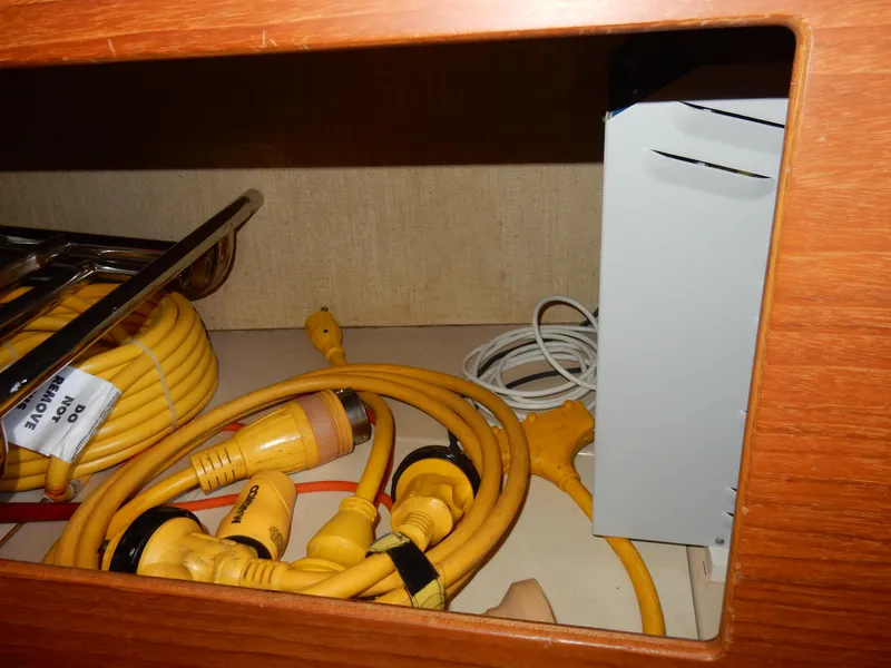 Slide: The Image of Storage compartment with yellow cables and equipment on a 1997 Island Packet 40 sailboat. - 44