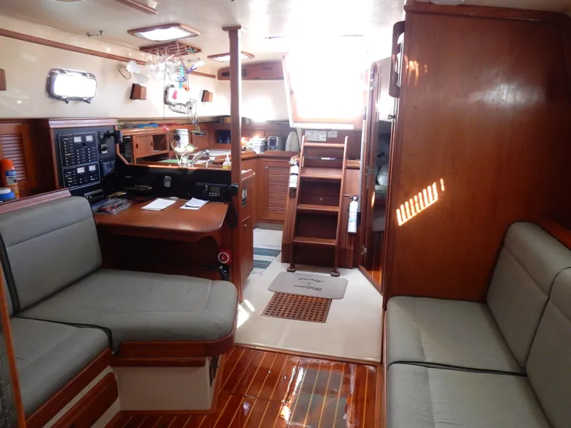 Slide: The Image of Interior of a 1997 Island Packet 40 sailboat, featuring wood finishes and seating area. - 9