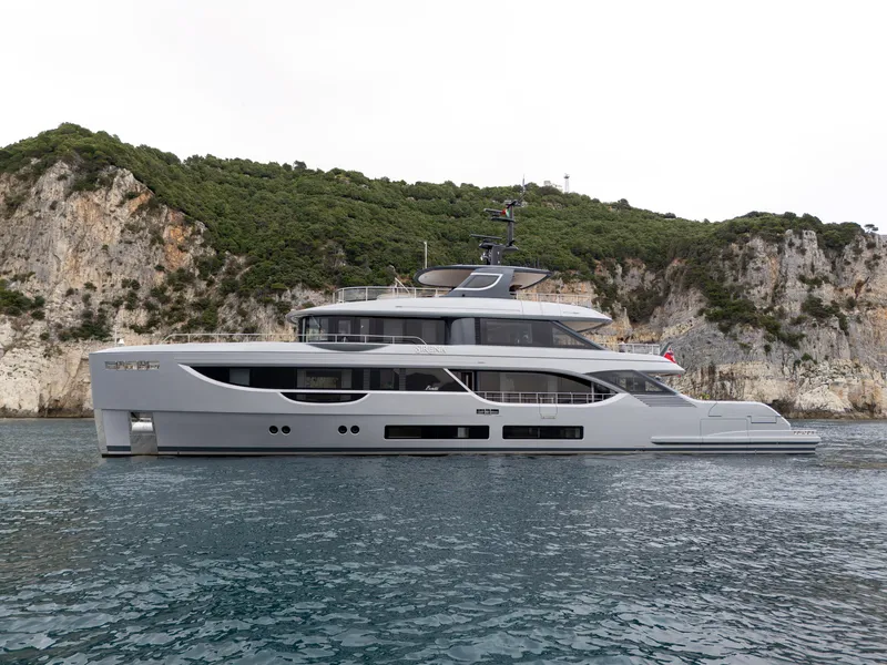 Slide: The Image of 2025 Benetti Oasis 34M yacht cruising near rocky coastline. - 2