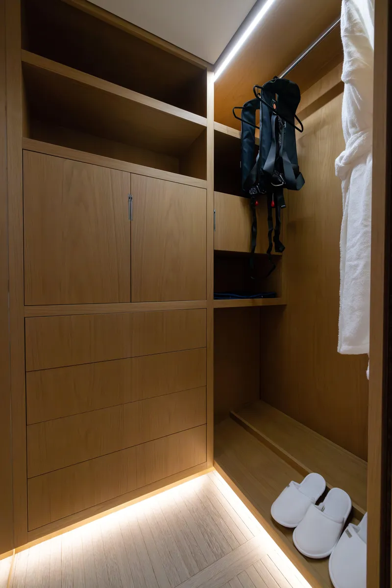 Slide: The Image of Luxurious wooden closet interior on Benetti Oasis 34M yacht, featuring shelves, robe, and slippers. - 32